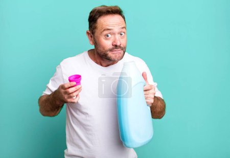 Foto de Hombre de mediana edad ama de llaves concepto con una ropa sucia cesta deporte entrenador concepto con una pelota de fútbol - Imagen libre de derechos