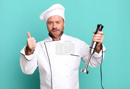 Foto de Hombre de mediana edad concepto de chef y una mano licuadora concepto entrenador deportivo con una pelota de fútbol - Imagen libre de derechos