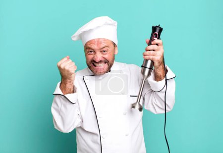 Photo for Middle age man chef concept and a hand blender sport coach concept with a soccer ball - Royalty Free Image