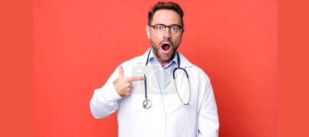 Photo for Middle age man looking shocked and surprised with mouth wide open, pointing to self. physician concept - Royalty Free Image