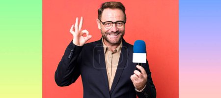 Photo for Middle age man feeling happy, showing approval with okay gesture. journalist and a microphone concept - Royalty Free Image