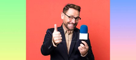 Photo for Middle age man feeling proud,smiling positively with thumbs up. journalist and a microphone concept - Royalty Free Image