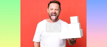 Photo for Middle age man with cheerful and rebellious attitude, joking and sticking tongue out. blank packages concept - Royalty Free Image
