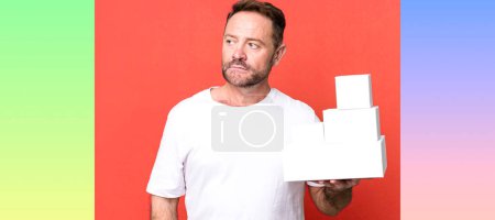 Photo for Middle age man feeling sad, upset or angry and looking to the side. blank packages concept - Royalty Free Image