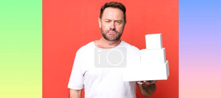 Photo for Middle age man feeling sad and whiney with an unhappy look and crying. blank packages concept - Royalty Free Image
