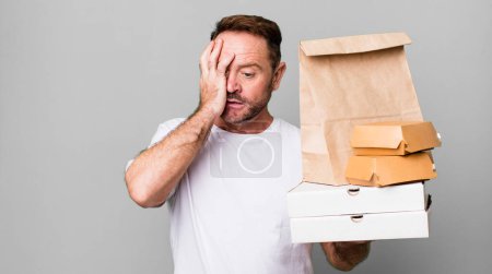 Téléchargez les photos : Homme d'âge moyen se sentant ennuyé, frustré et somnolent après un fatigant. livraison et fast food concept à emporter - en image libre de droit