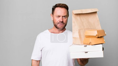 Téléchargez les photos : Homme d'âge moyen se sentant perplexe et confus. livraison et fast food concept à emporter - en image libre de droit