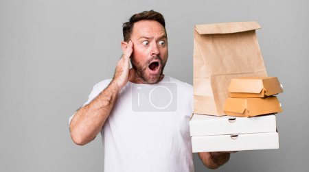 Foto de Hombre de mediana edad sentirse feliz, emocionado y sorprendido. entrega y comida rápida para llevar concepto - Imagen libre de derechos