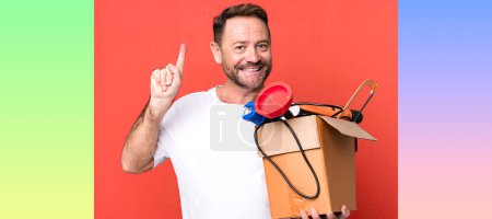 Foto de Hombre de mediana edad sonriendo y buscando amigable, mostrando el número uno. manitas con caja de herramientas - Imagen libre de derechos