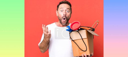 Photo for Middle age man amazed, shocked and astonished with an unbelievable surprise. handyman with a toolbox - Royalty Free Image