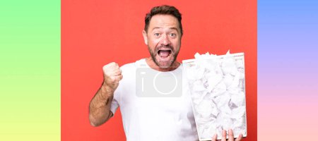 Foto de Hombre de mediana edad sintiéndose sorprendido, riendo y celebrando el éxito. bolas de papel papelera - Imagen libre de derechos
