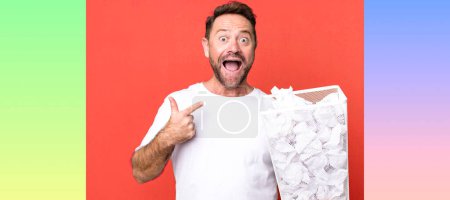 Photo for Middle age man feeling happy and pointing to self with an excited. paper balls trash basket - Royalty Free Image
