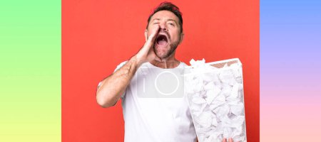 Photo for Middle age man feeling happy,giving a big shout out with hands next to mouth. paper balls trash basket - Royalty Free Image