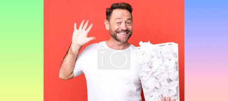 Foto de Hombre de mediana edad sonriendo y buscando amigable, mostrando el número cinco. bolas de papel papelera - Imagen libre de derechos