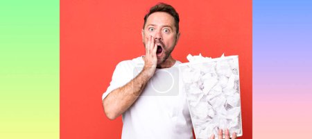 Photo for Middle age man feeling shocked and scared. paper balls trash basket - Royalty Free Image