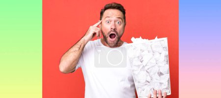 Photo for Middle age man looking surprised, realizing a new thought, idea or concept. paper balls trash basket - Royalty Free Image