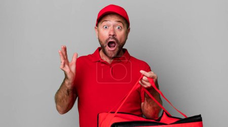 Foto de Hombre de mediana edad sorprendido, sorprendido y asombrado con una sorpresa increíble. repartidor de pizza - Imagen libre de derechos
