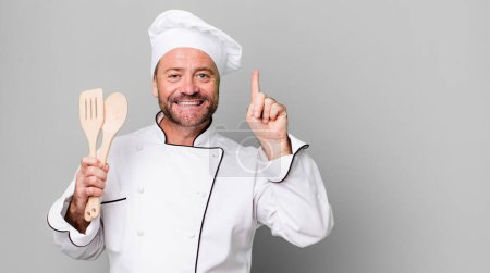 Photo for Middle age man smiling and looking friendly, showing number one. chef and tools concept - Royalty Free Image