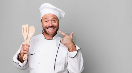 Photo for Middle age man smiling confidently pointing to own broad smile. chef and tools concept - Royalty Free Image
