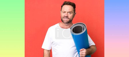 Photo for Middle age man looking puzzled and confused. with a yoga matt. fitness concept - Royalty Free Image