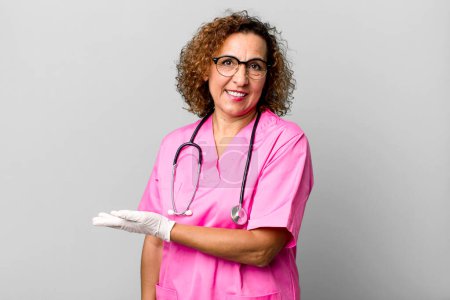 Photo for Pretty middle age woman smiling cheerfully, feeling happy and showing a concept. nurse concept - Royalty Free Image