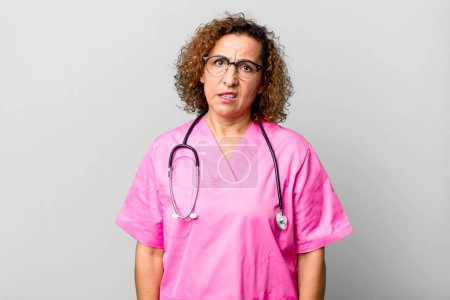 Photo for Pretty middle age woman feeling puzzled and confused. nurse concept - Royalty Free Image