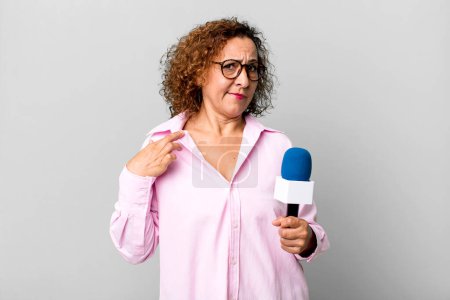 Photo for Pretty middle age woman looking arrogant, successful, positive and proud. tv presenter with a microphone concept - Royalty Free Image