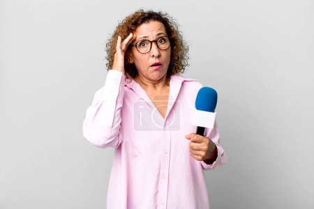 Photo for Pretty middle age woman looking surprised, realizing a new thought, idea or concept. tv presenter with a microphone concept - Royalty Free Image