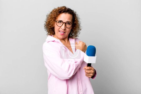 Photo for Pretty middle age woman feeling happy and facing a challenge or celebrating. tv presenter with a microphone concept - Royalty Free Image