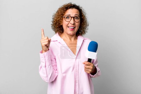 Photo for Pretty middle age woman feeling like a happy and excited genius after realizing an idea. tv presenter with a microphone concept - Royalty Free Image