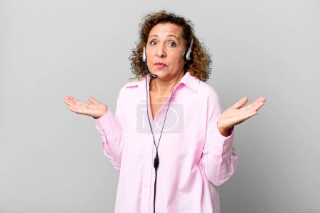 Foto de Mujer bastante de mediana edad sintiéndose desconcertado y confundido y dudando con un auricular. concepto de telemarketing - Imagen libre de derechos