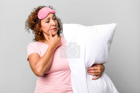 Photo for Pretty middle age woman smiling with a happy, confident expression with hand on chin wearing pajamas night wear and a pillow - Royalty Free Image