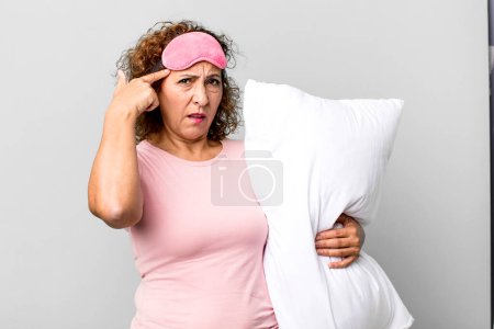 Foto de Mujer de mediana edad se siente confundido y perplejo, mostrando que usted está loco usando ropa de noche pijama y una almohada - Imagen libre de derechos