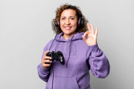 Foto de Mujer bastante mediana edad sentirse feliz, mostrando aprobación con gesto bien jugando juego virtual. concepto de jugador - Imagen libre de derechos