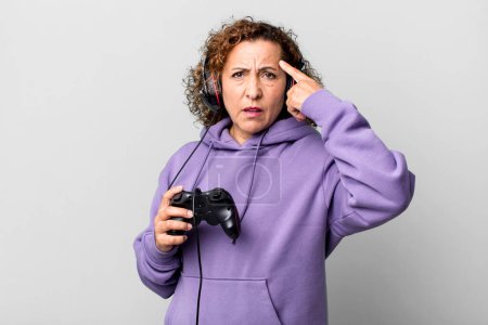Photo for Pretty middle age woman feeling confused and puzzled, showing you are insane playing virtual game. gamer concept - Royalty Free Image