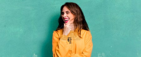 Foto de Hispanic pretty woman smiling with a happy, confident expression with hand on chin. guilt concept - Imagen libre de derechos