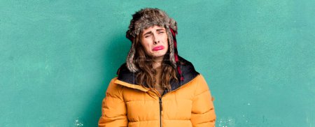 Foto de Mujer bonita hispana sintiéndose triste y llorona con una mirada infeliz y llorando. usando un anorak. concepto frío e invierno - Imagen libre de derechos