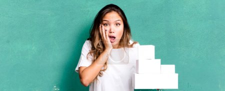 Photo for Hispanic pretty woman feeling shocked and scared with white boxes packages - Royalty Free Image