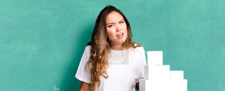 Téléchargez les photos : Hispanic pretty woman feeling puzzled and confused with white boxes packages - en image libre de droit