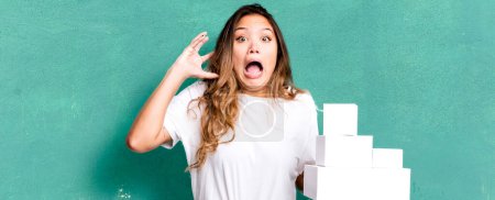 Photo for Hispanic pretty woman screaming with hands up in the air with white boxes packages - Royalty Free Image