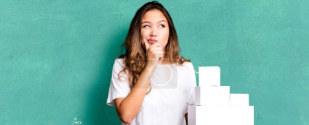 Photo for Hispanic pretty woman thinking, feeling doubtful and confused with white boxes packages - Royalty Free Image