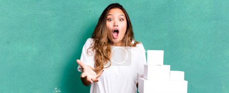 Photo for Hispanic pretty woman feeling extremely shocked and surprised with white boxes packages - Royalty Free Image