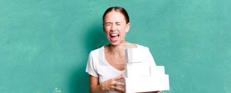 Téléchargez les photos : Caucasian pretty woman shouting aggressively, looking very angry with white boxes packages - en image libre de droit