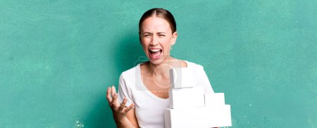 Photo for Caucasian pretty woman looking angry, annoyed and frustrated with white boxes packages - Royalty Free Image