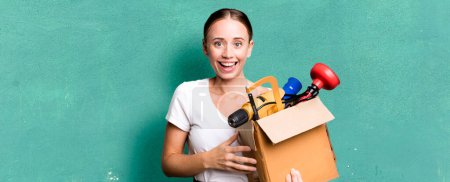 Photo for Caucasian pretty woman looking happy and pleasantly surprised with a tool box. repair home concept - Royalty Free Image