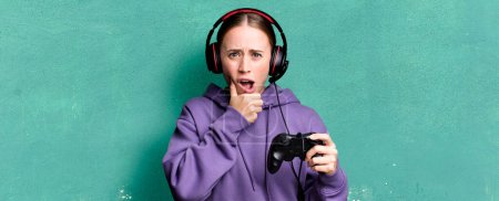 Photo for Caucasian pretty woman with mouth and eyes wide open and hand on chin. gamer concept - Royalty Free Image