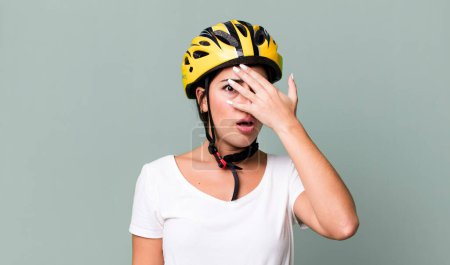 Foto de Looking shocked, scared or terrified, covering face with hand. bike helmet concept - Imagen libre de derechos