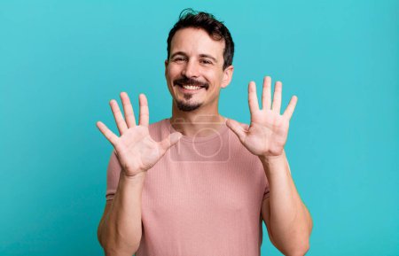 Photo for Smiling and looking friendly, showing number ten or tenth with hand forward, counting down - Royalty Free Image