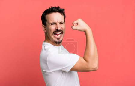 Photo for Feeling happy, satisfied and powerful, flexing fit and muscular biceps, looking strong after the gym - Royalty Free Image
