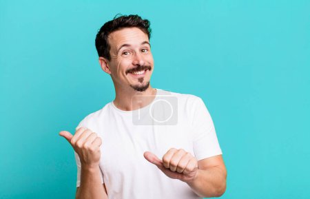 Photo for Smiling cheerfully and casually pointing to copy space on the side, feeling happy and satisfied - Royalty Free Image
